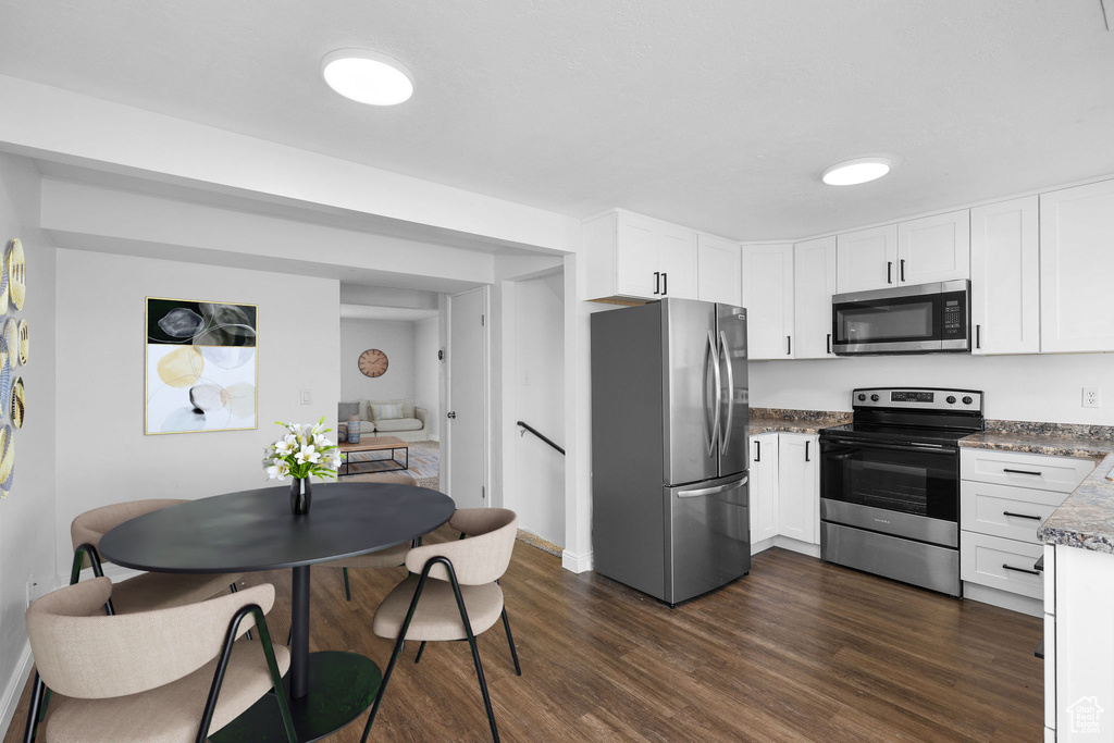 Kitchen with stainless steel appliances, dark wood-type flooring, and white cabinetry