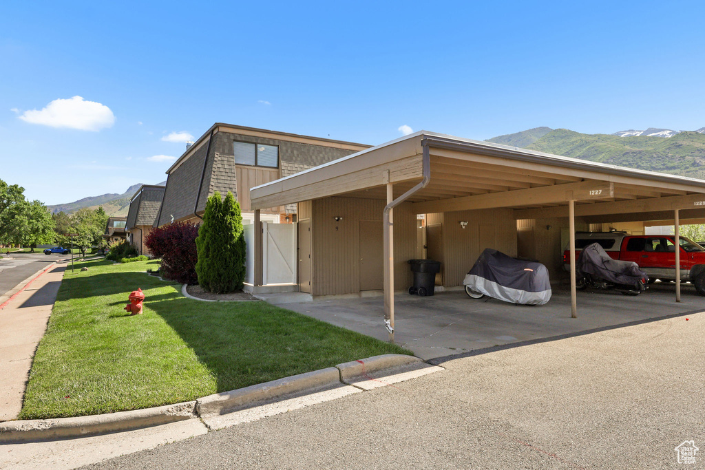 View of front facade with a mountain view, a front lawn, and covered parking
