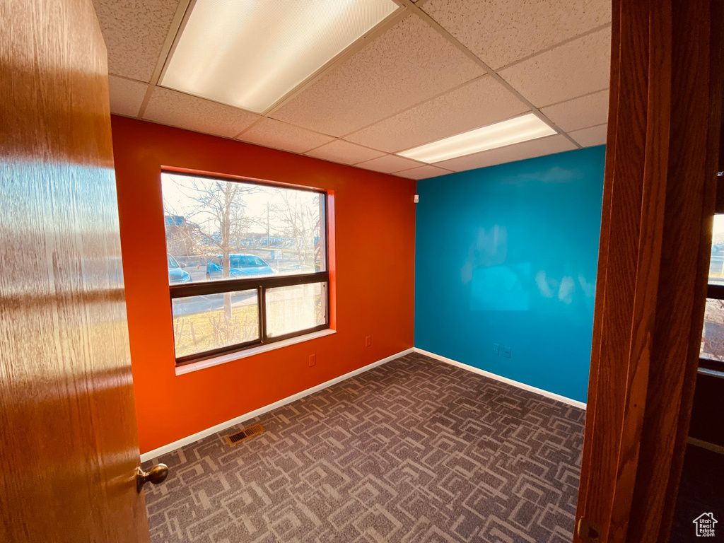 Empty room with a drop ceiling and baseboards