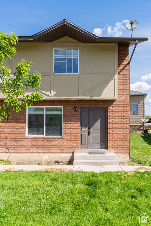 Back of house featuring a lawn, brick siding, and entry steps
