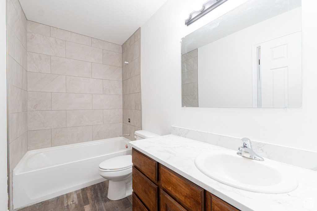 Bathroom featuring wood finished floors, vanity, toilet, and tub / shower combination