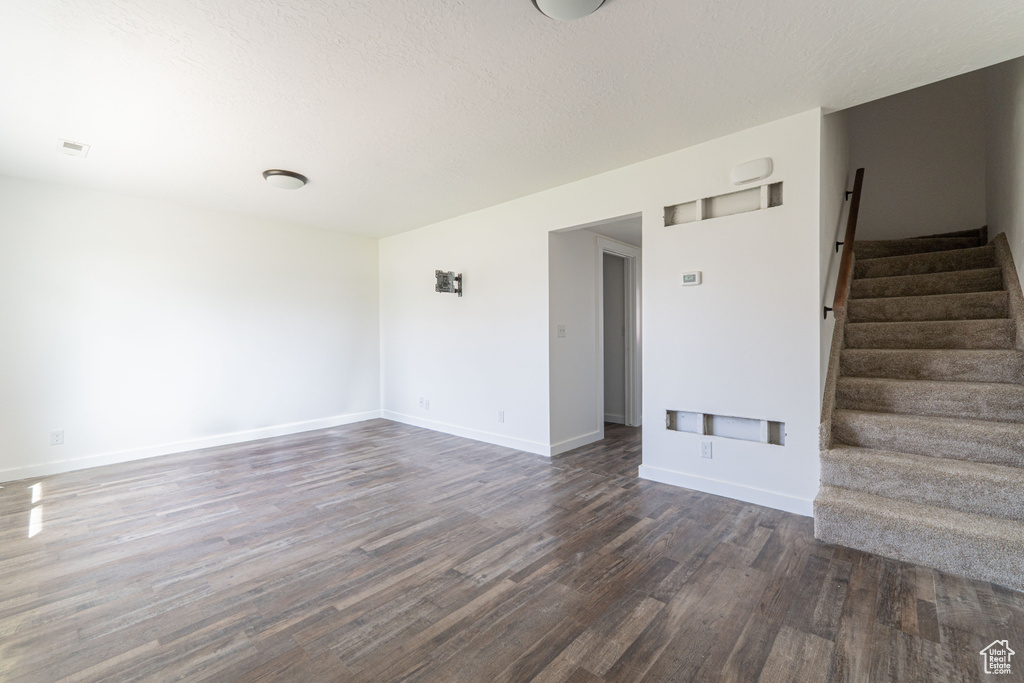 Unfurnished room with dark wood finished floors, stairs, and baseboards