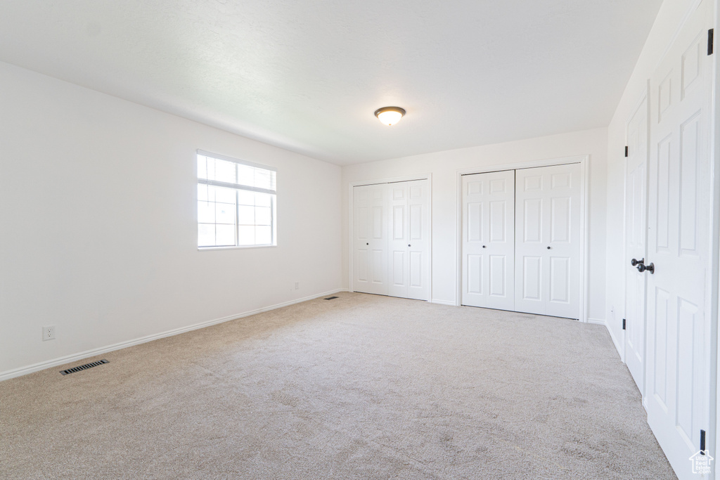 Unfurnished bedroom featuring two closets, carpet flooring, and baseboards