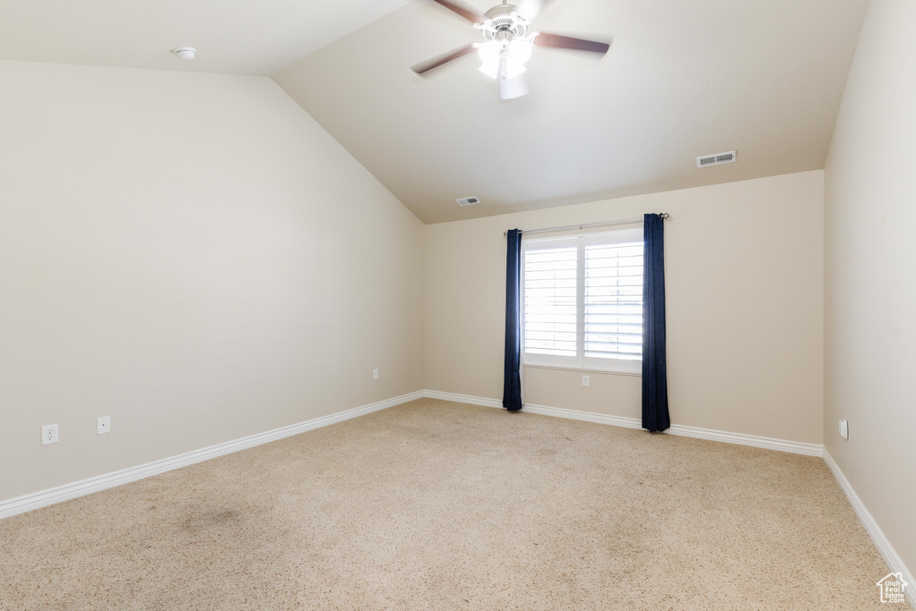 Spare room with light colored carpet, a ceiling fan, lofted ceiling, and baseboards