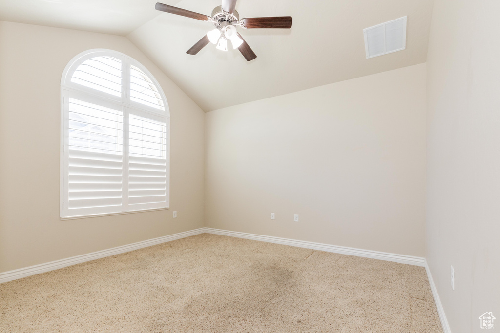 Empty room featuring vaulted ceiling, ceiling fan, baseboards, and carpet