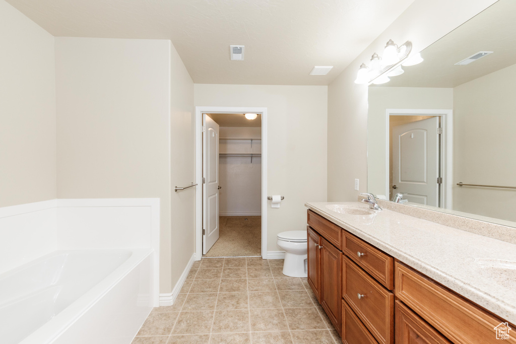 Bathroom with double vanity, a bath, toilet, a spacious closet, and baseboards