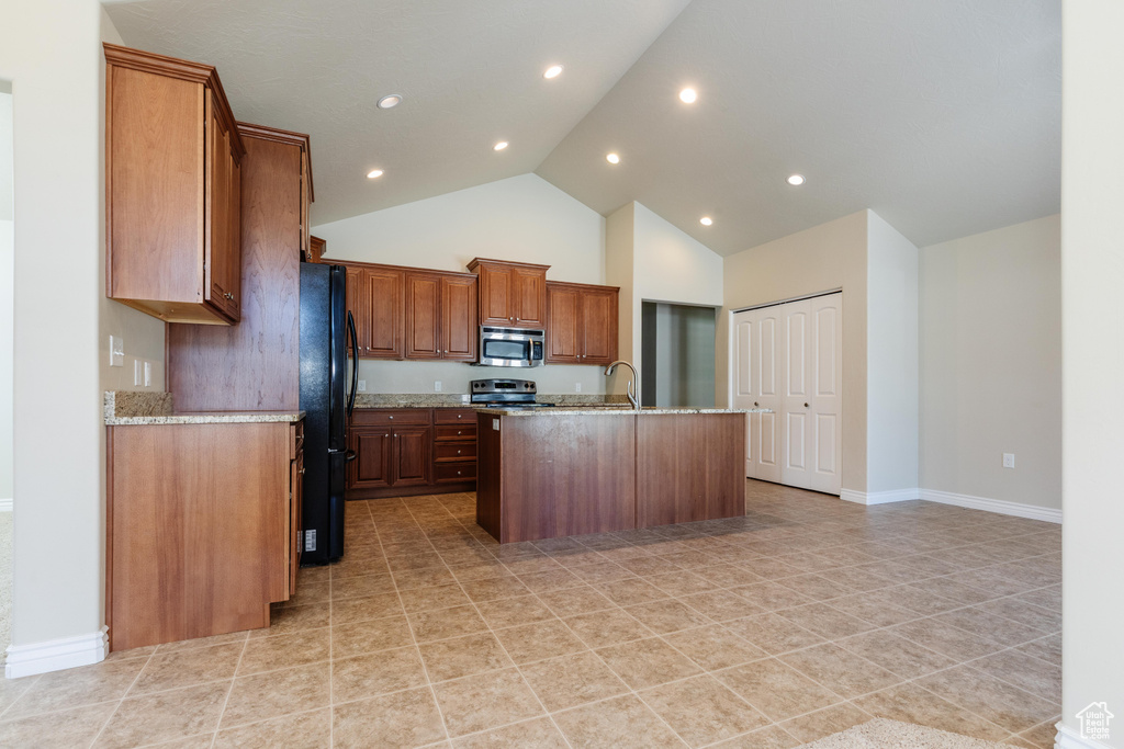 Kitchen with stainless steel appliances, high vaulted ceiling, a center island with sink, light stone counters, and baseboards
