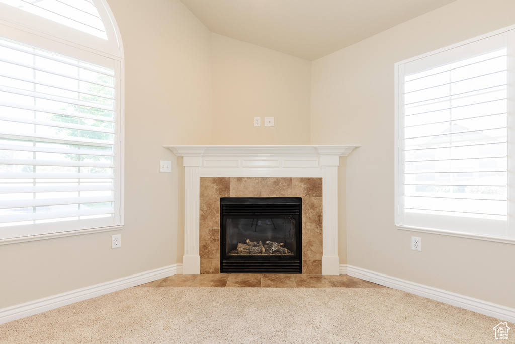 Detailed view of a tiled fireplace, carpet floors, and baseboards
