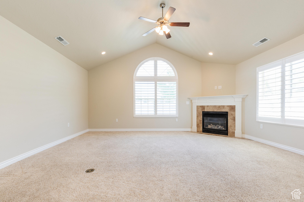 Unfurnished living room with a ceiling fan, light carpet, a high end fireplace, vaulted ceiling, and baseboards