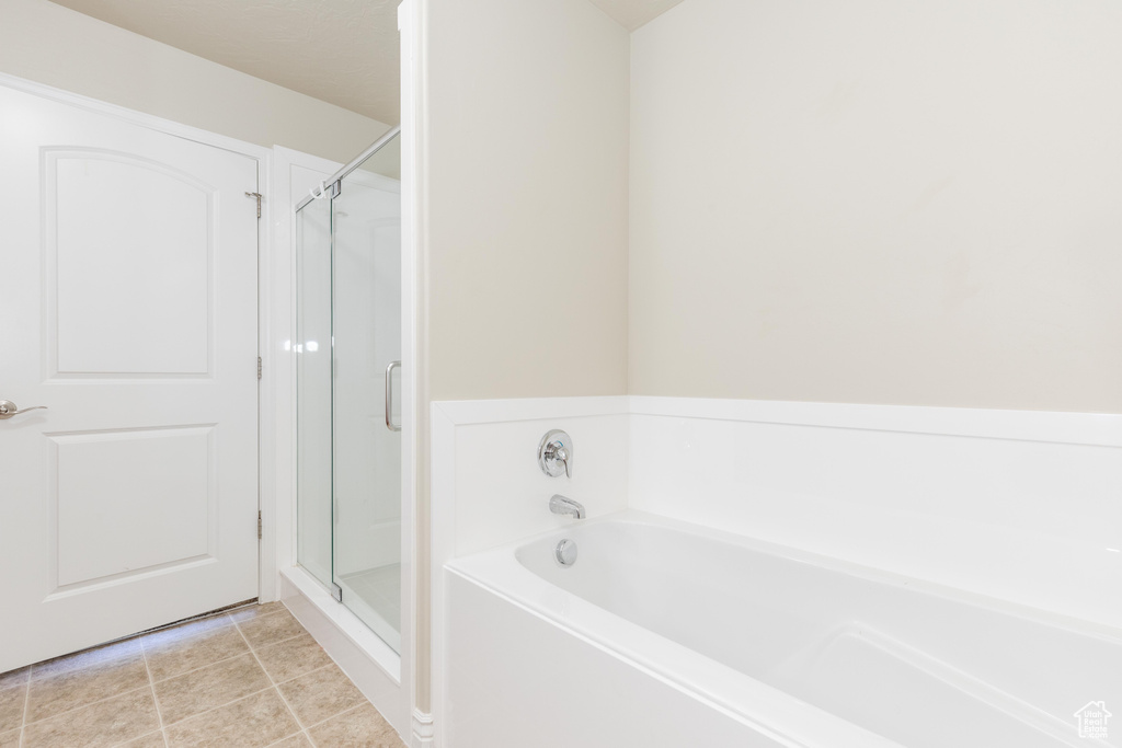 Full bath featuring a bath, a shower stall, and tile patterned flooring