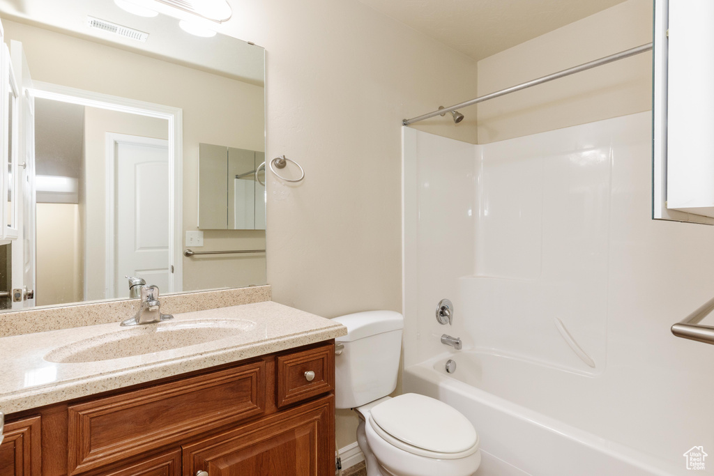 Bathroom featuring vanity, toilet, and washtub / shower combination