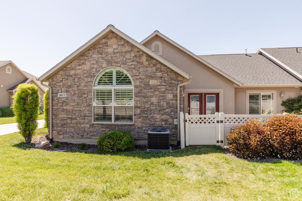 View of front of house with stone siding, a front lawn, and stucco siding