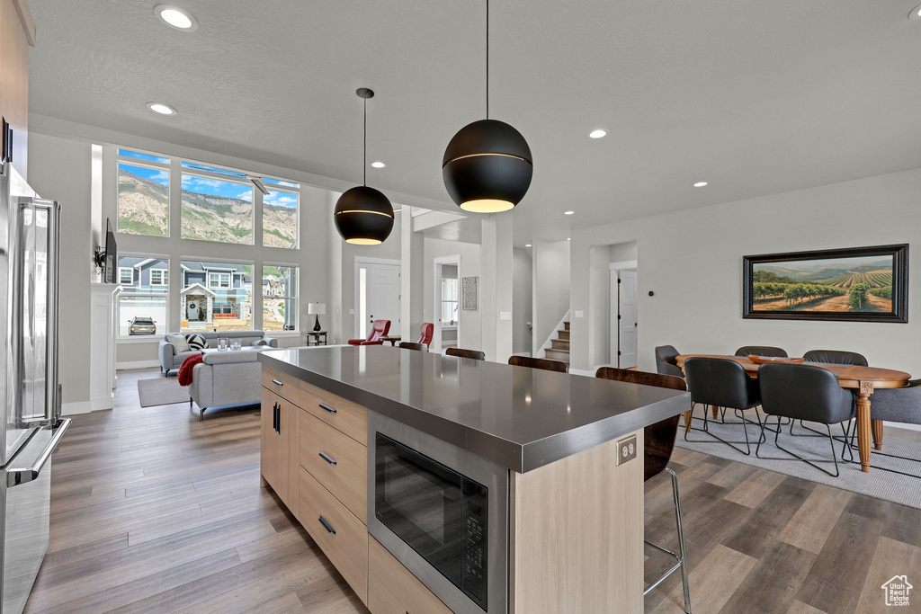 Kitchen with modern cabinets, appliances with stainless steel finishes, light brown cabinets, open floor plan, and a center island
