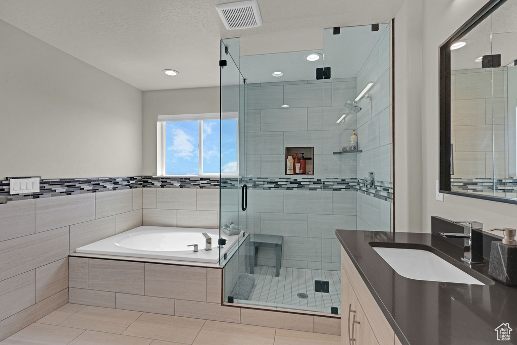 Bathroom featuring vanity, a bath, a shower stall, recessed lighting, and tile patterned flooring