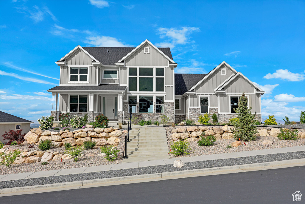 Craftsman house with board and batten siding, stone siding, a shingled roof, and covered porch