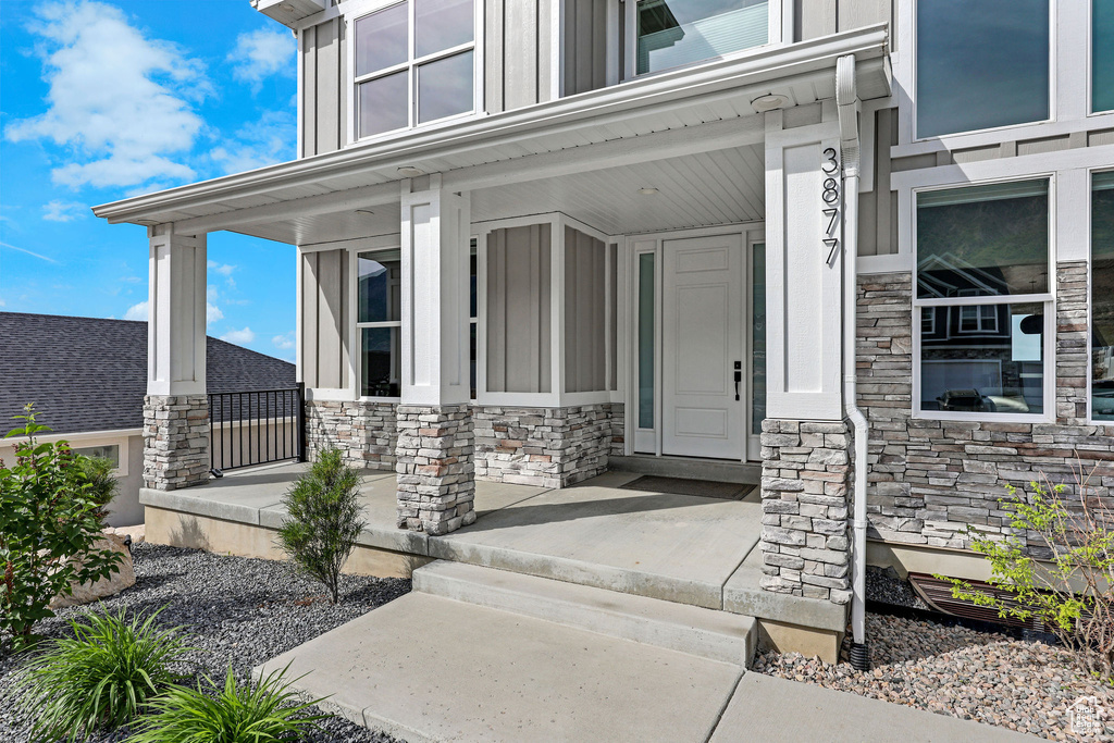 Entrance to property with a porch, stone siding, and board and batten siding