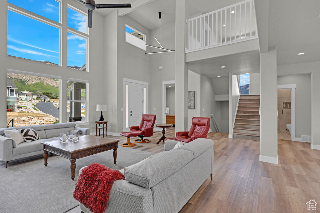 Living area with wood finished floors, stairs, baseboards, a high ceiling, and recessed lighting
