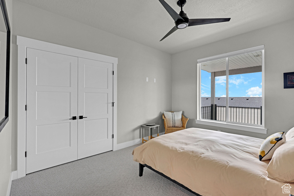 Carpeted bedroom featuring baseboards, a ceiling fan, and a closet