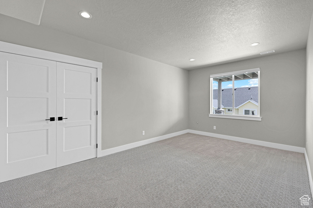 Unfurnished bedroom with a textured ceiling, carpet floors, recessed lighting, baseboards, and a closet