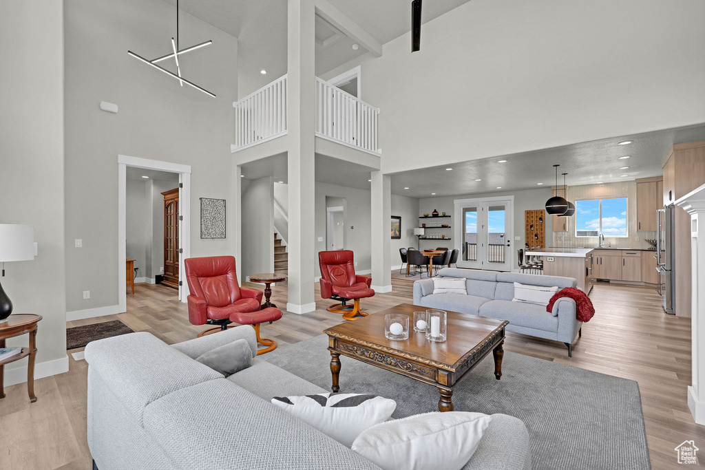 Living area with light wood-style floors, stairs, baseboards, a towering ceiling, and recessed lighting