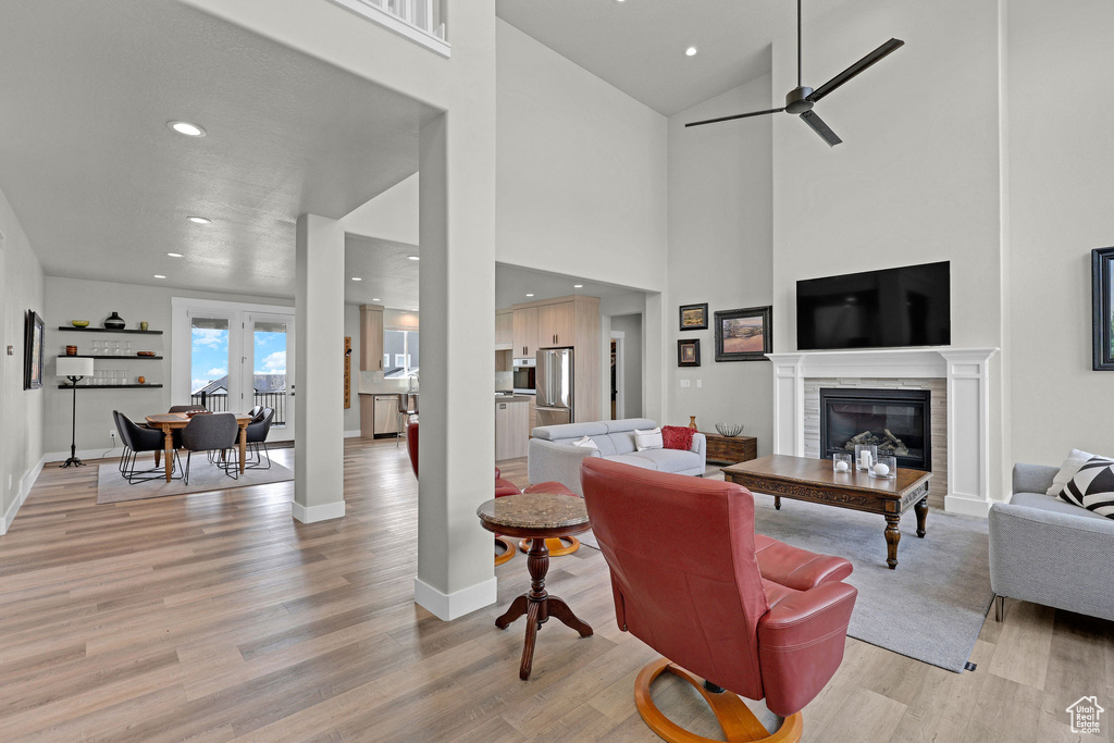 Living area featuring light wood-style flooring, recessed lighting, a ceiling fan, a glass covered fireplace, and baseboards
