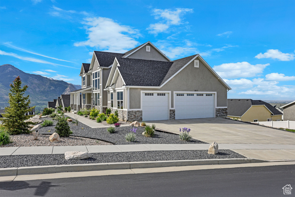 View of front of house with stone siding, stucco siding, an attached garage, driveway, and a mountain view