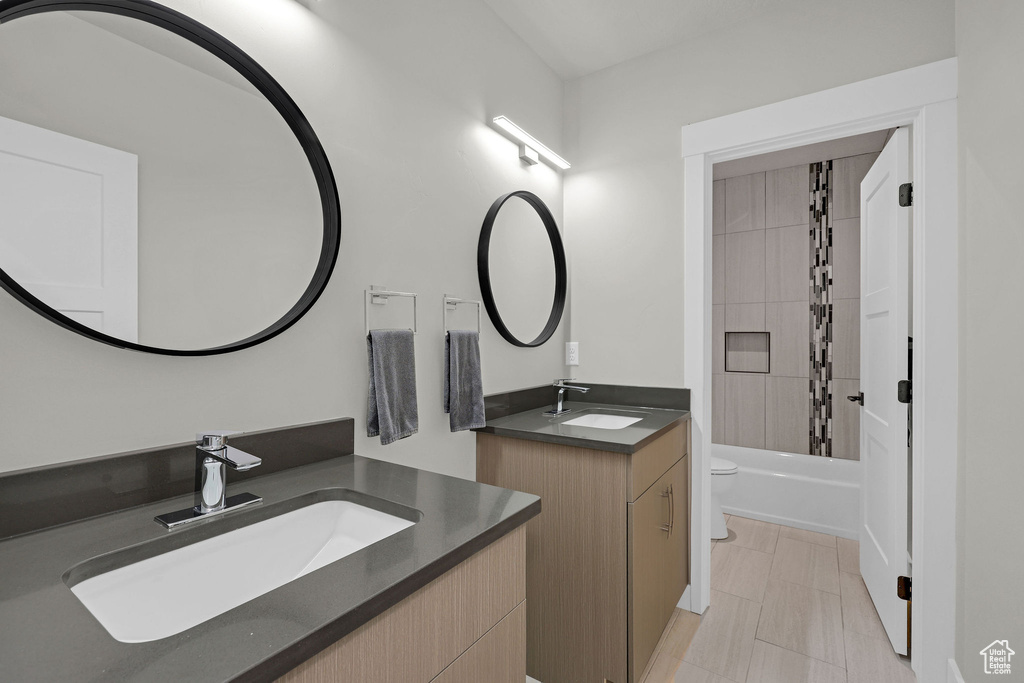 Bathroom featuring toilet, two vanities, and shower / washtub combination
