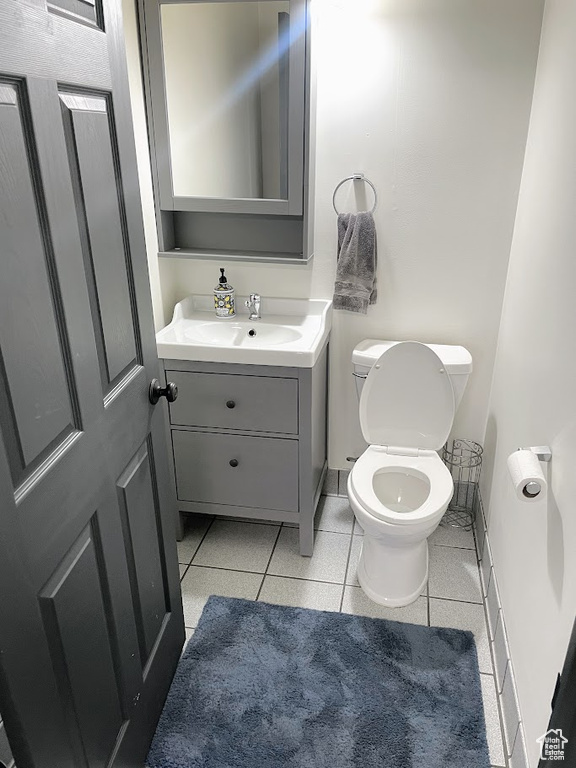 Half bathroom featuring vanity, toilet, tile patterned floors, and baseboards