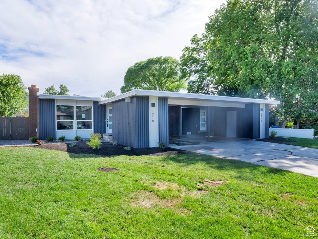 Mid-century inspired home with an attached carport, driveway, and a chimney