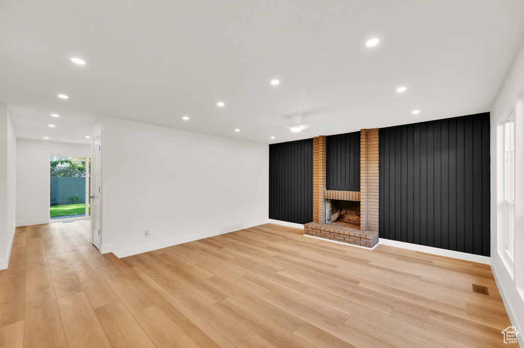Unfurnished living room with ceiling fan, recessed lighting, light wood finished floors, baseboards, and a brick fireplace