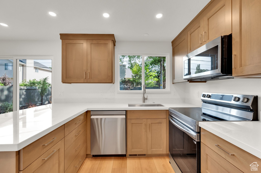 Kitchen with stainless steel appliances, a sink, recessed lighting, a peninsula, and light countertops