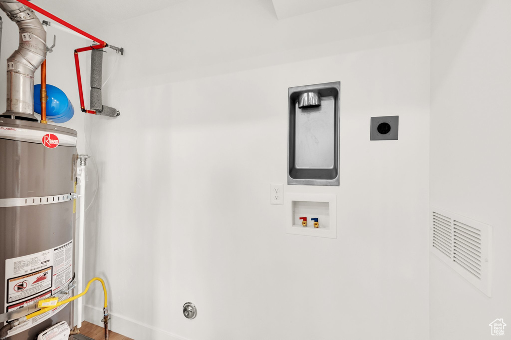 Laundry room with hookup for an electric dryer, washer hookup, secured water heater, and baseboards