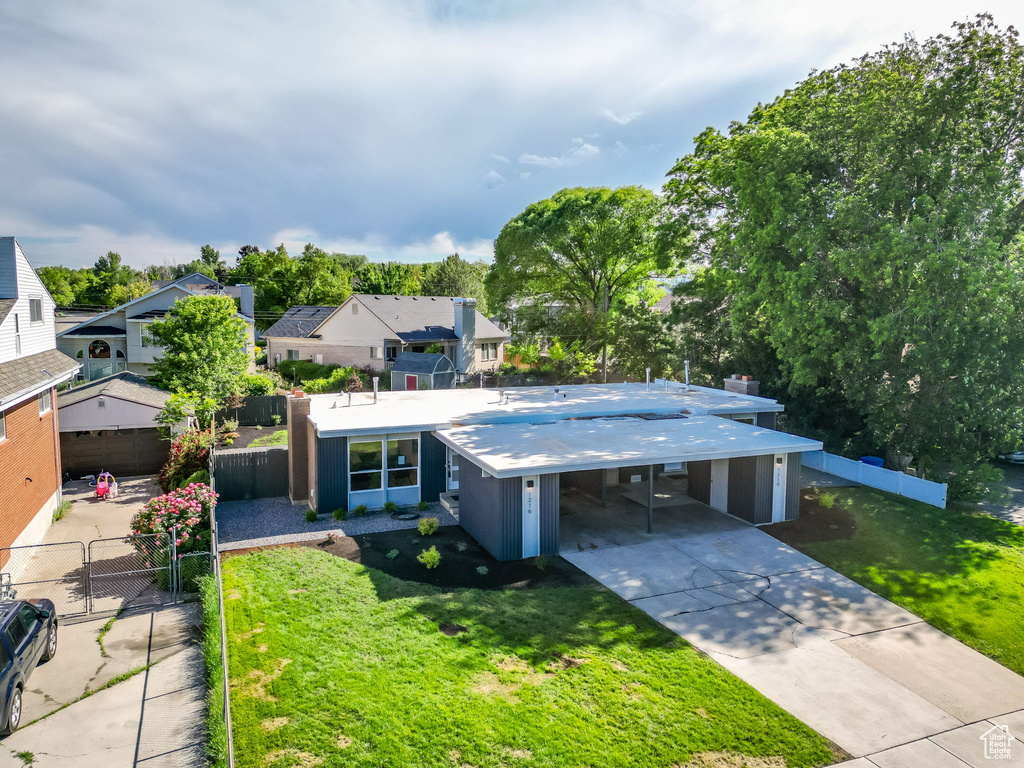 View of front of home featuring a chimney, concrete driveway, a residential view, an attached carport, and a gate