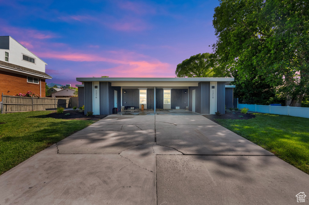 Single story home with board and batten siding, driveway, and a carport