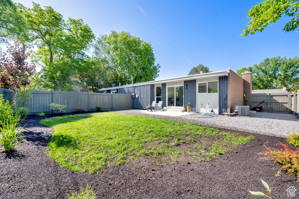 Back of property featuring a patio area, a chimney, central air condition unit, and a gate