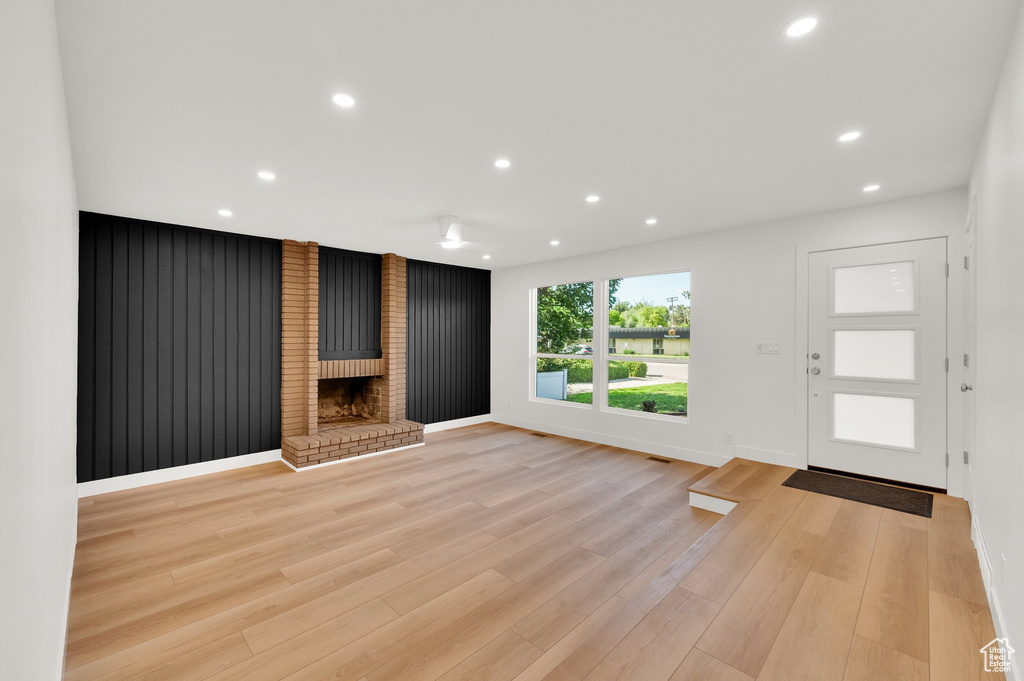 Unfurnished living room with recessed lighting, a brick fireplace, light wood-style floors, and baseboards