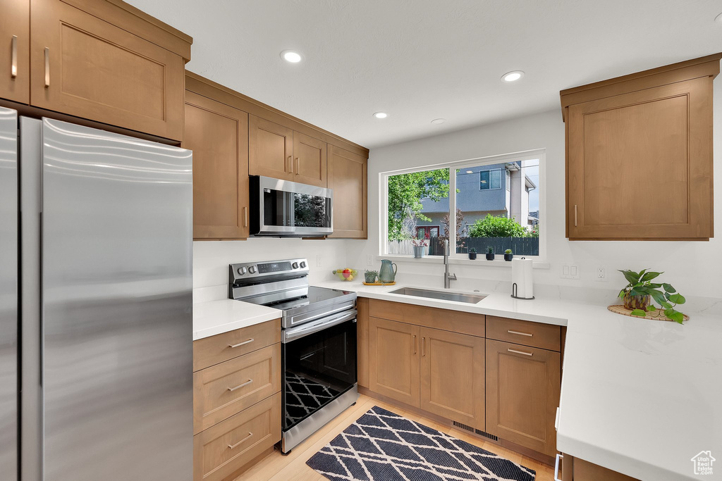 Kitchen featuring stainless steel appliances, a sink, recessed lighting, light countertops, and light wood-style flooring