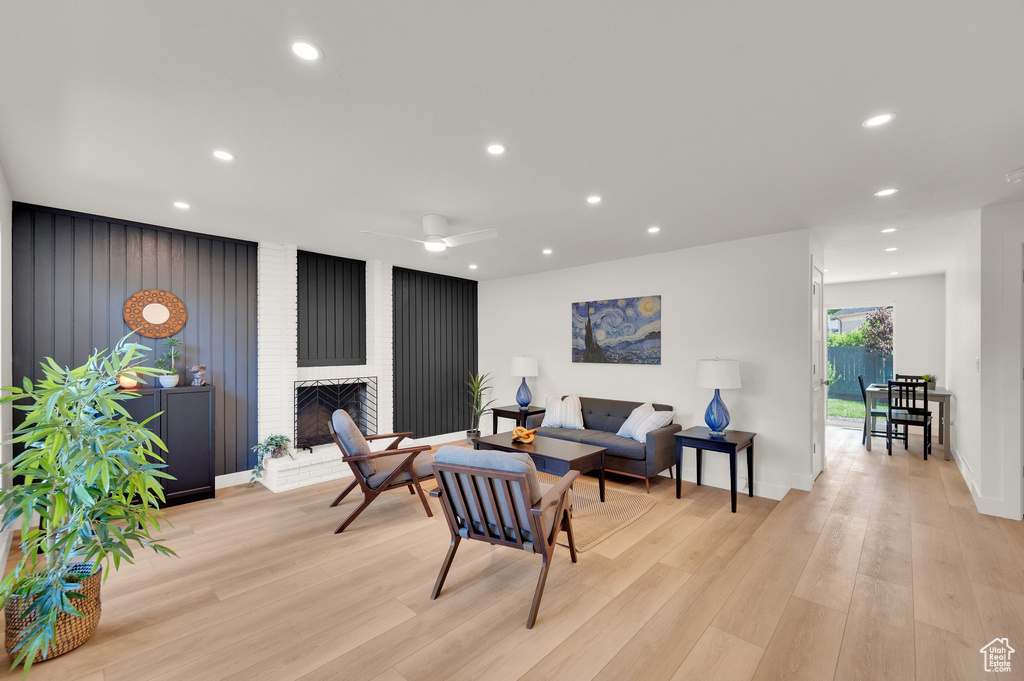 Living area with light wood finished floors, recessed lighting, a fireplace, baseboards, and ceiling fan