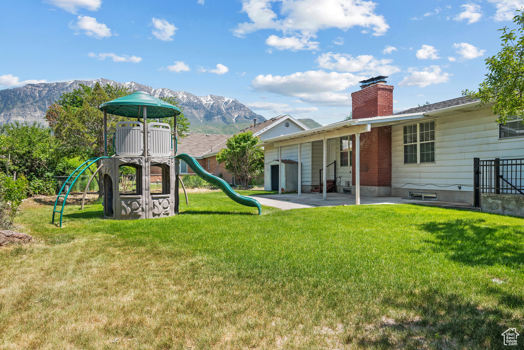 Back of house with a chimney, a mountain view, and a patio