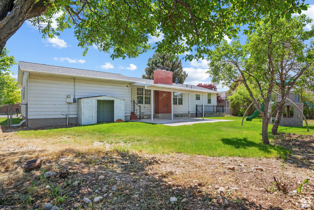 Rear view of property featuring entry steps, a patio, a chimney, and a playground
