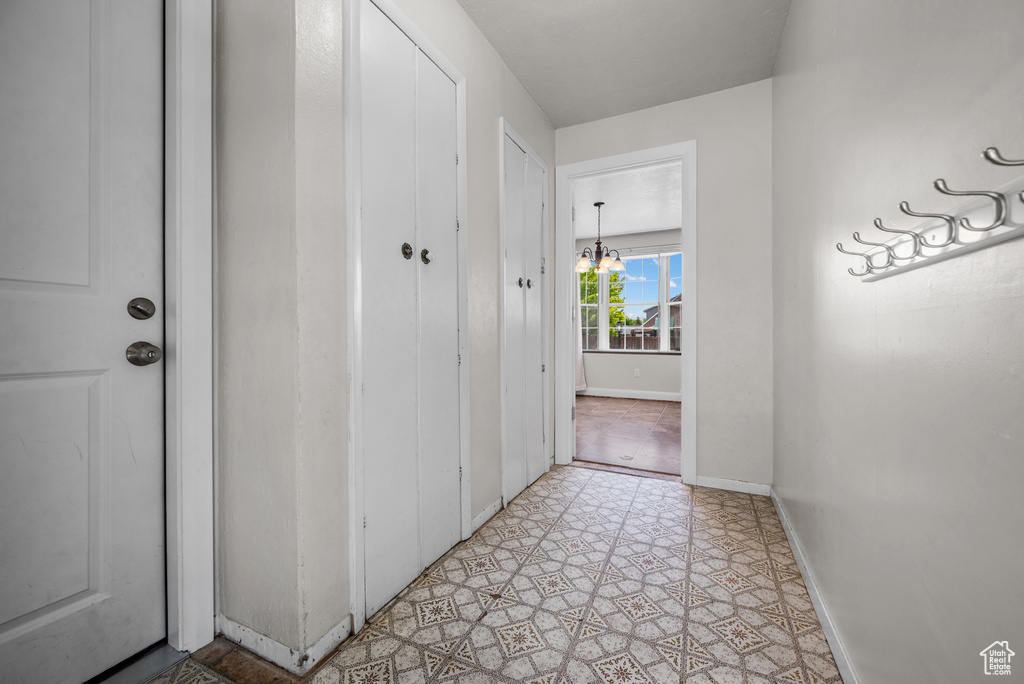 Hall featuring baseboards and a chandelier