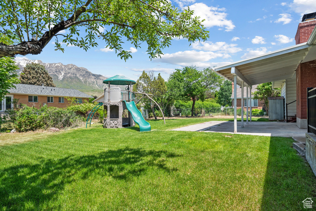 View of yard featuring a playground, a mountain view, and a patio area