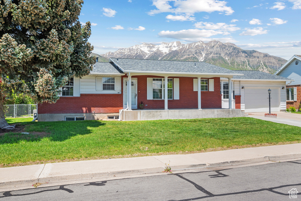 Single story home with a mountain view, brick siding, an attached garage, covered porch, and driveway