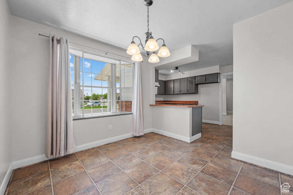 Kitchen featuring a chandelier, a peninsula, baseboards, and hanging light fixtures