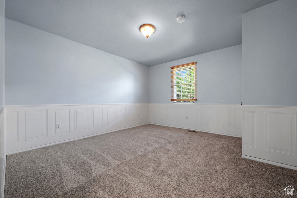 Carpeted empty room featuring wainscoting