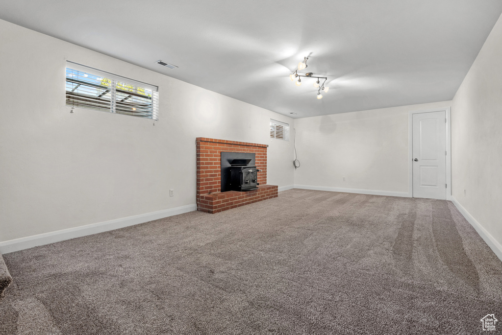 Unfurnished living room with a wood stove, carpet flooring, and baseboards