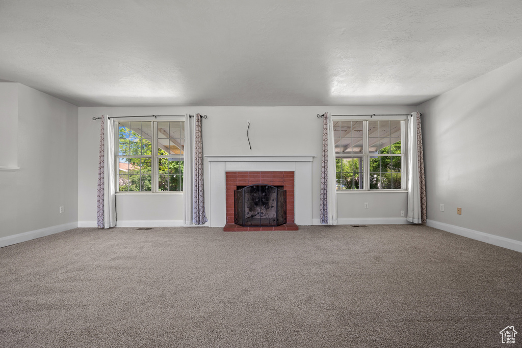 Unfurnished living room featuring healthy amount of natural light, carpet flooring, and baseboards
