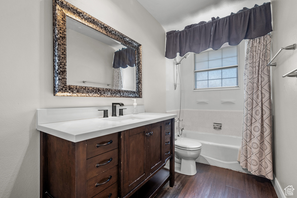 Bathroom with toilet, shower / bath combo, vanity, and wood finished floors