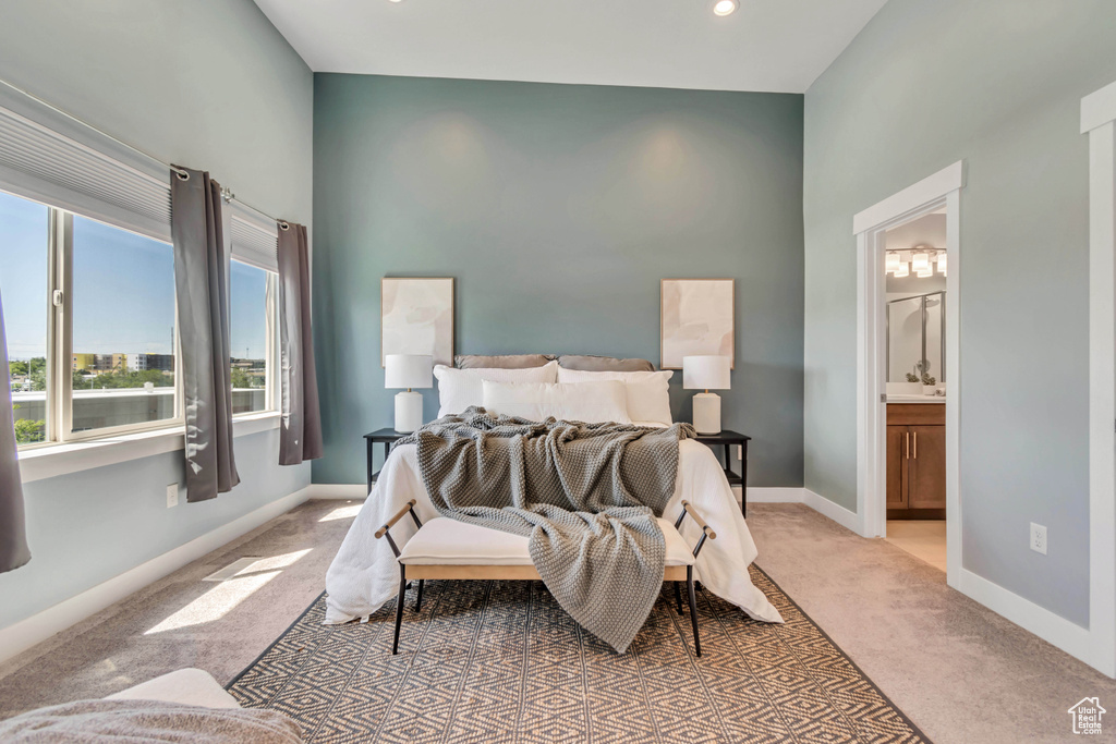 Bedroom featuring light colored carpet, baseboards, and ensuite bath