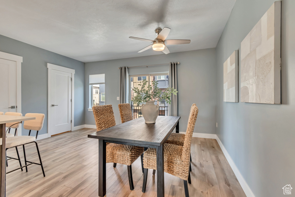 Dining room with a ceiling fan, light wood-style floors, and baseboards